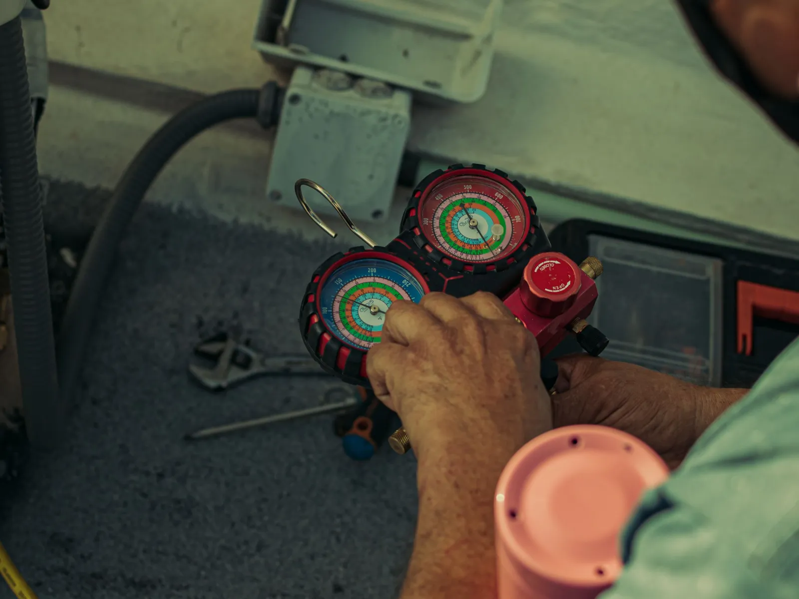 Hands adjusting a refrigerant manifold gauge set during air-conditioning maintenance