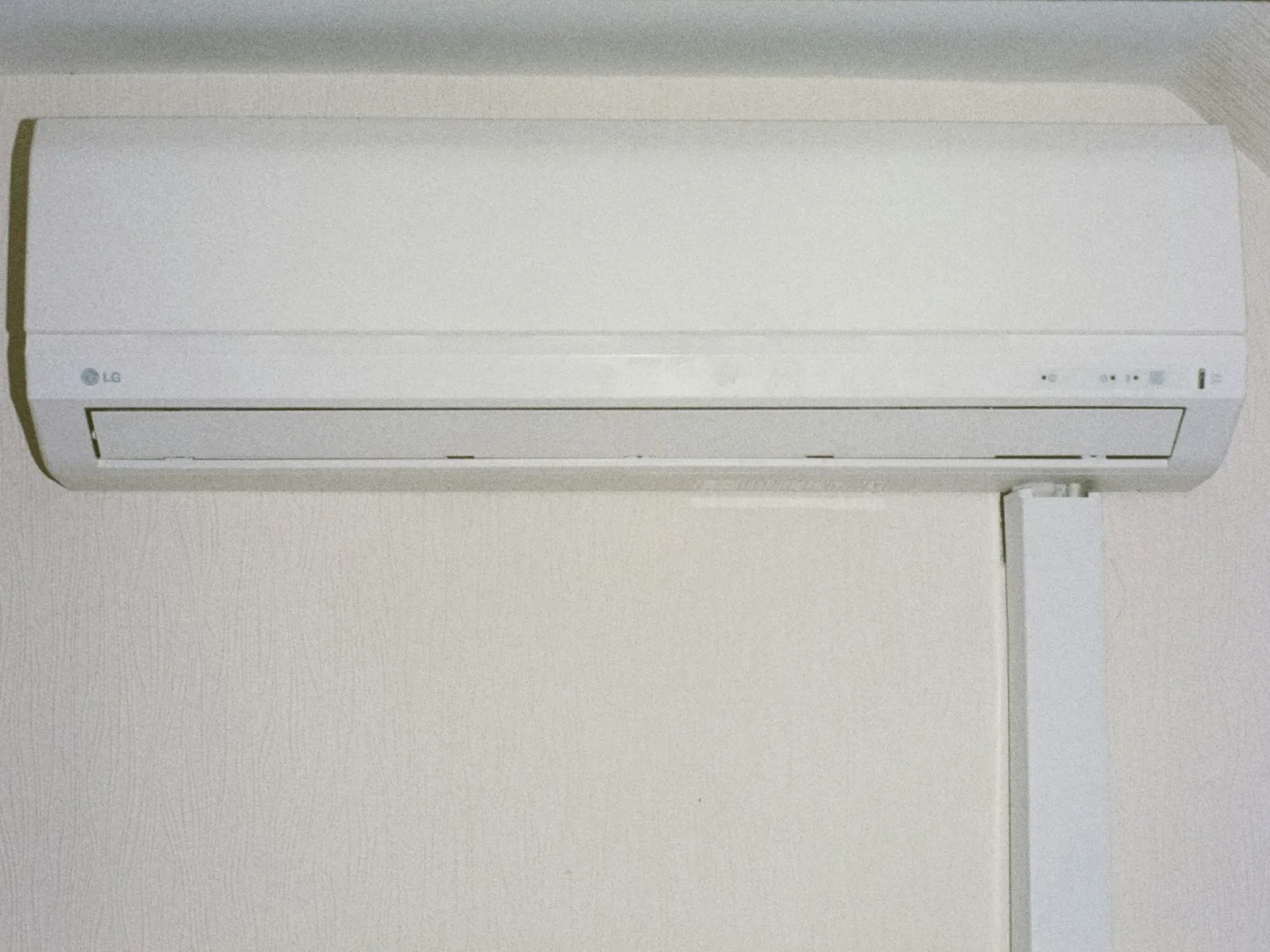 Wall-mounted split air-conditioner indoor unit above a doorway on a plain wall