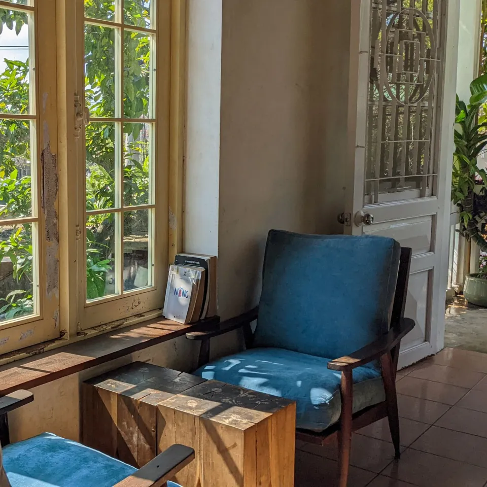 Sunlit cafe corner with wooden armchairs, blue cushions and tall garden windows