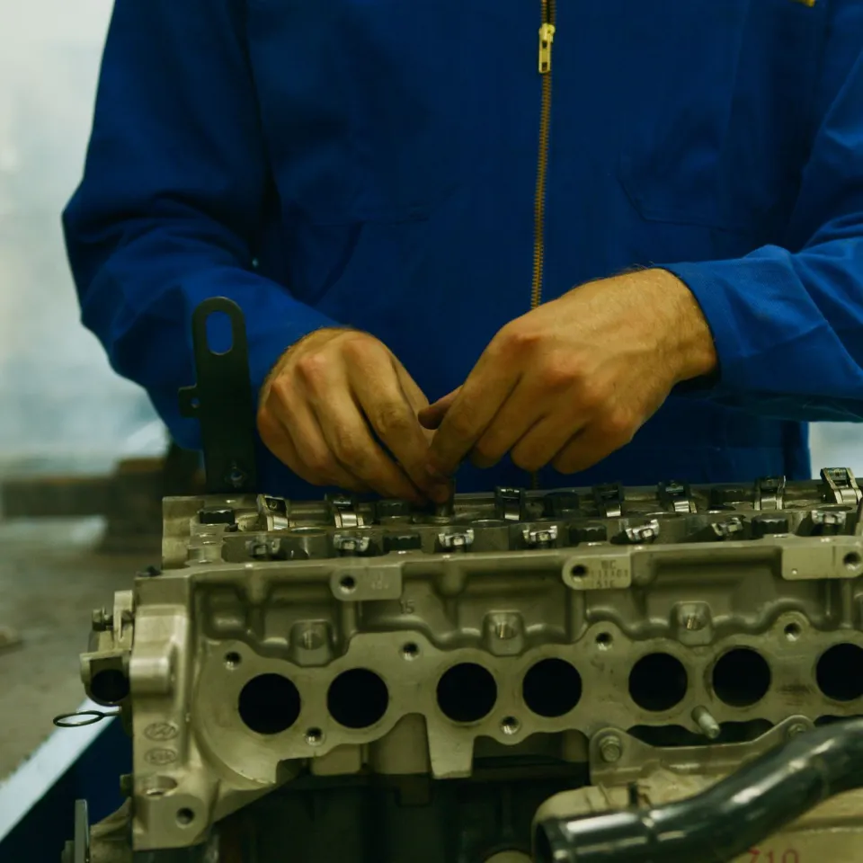 Close-up of a technician's hands assembling a cylinder head on a bench