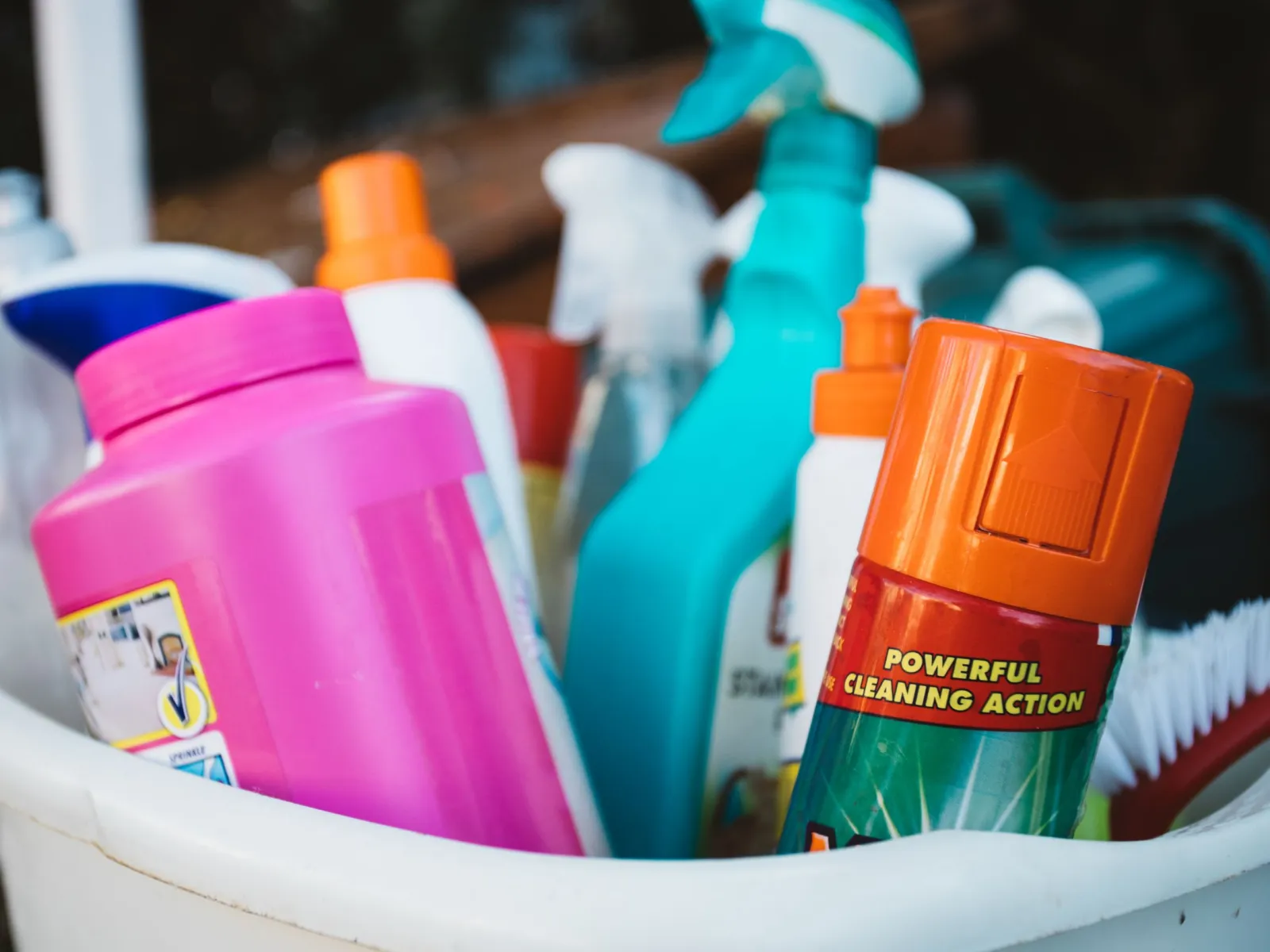 Assorted cleaning spray bottles and detergents packed in a white bucket