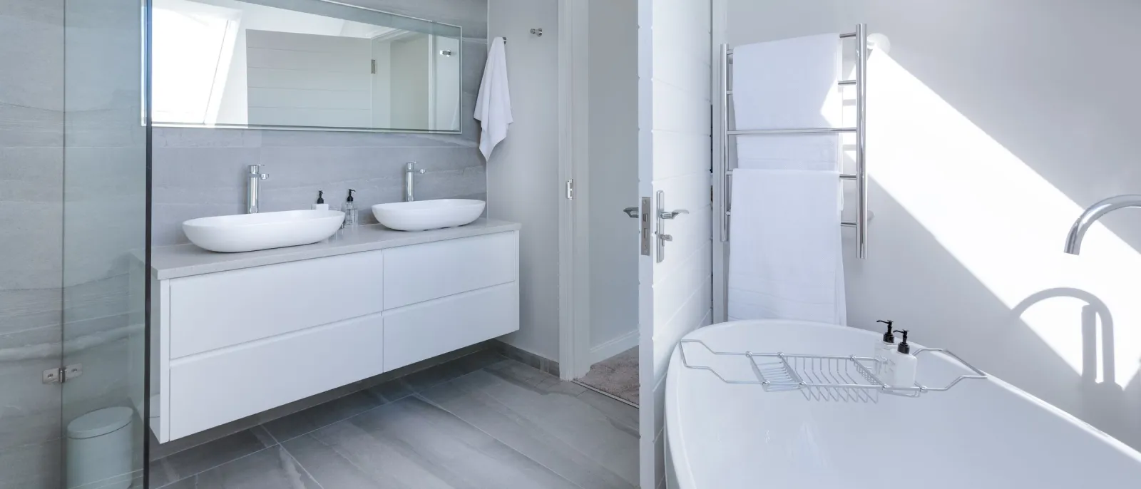 Spotless white bathroom with twin basins, bathtub, and glass shower
