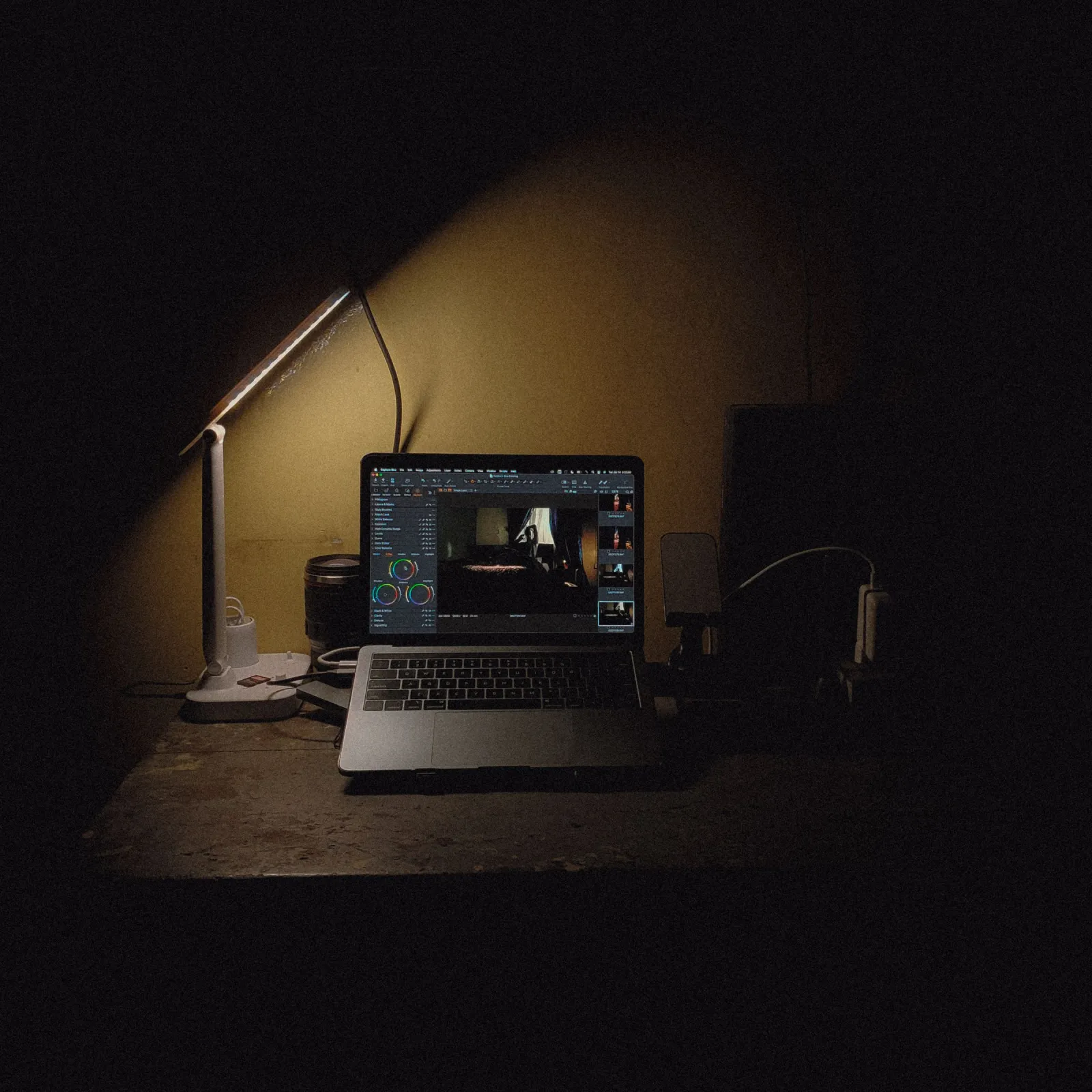 Laptop and desk lamp glowing on a dark desk at night