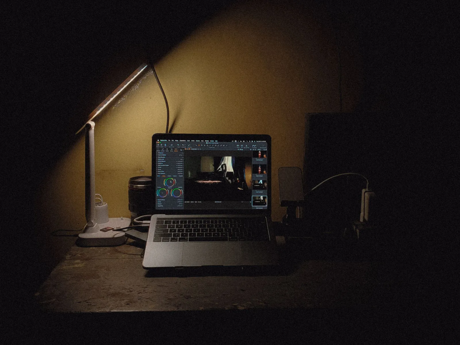 Laptop and desk lamp glowing on a dark desk at night