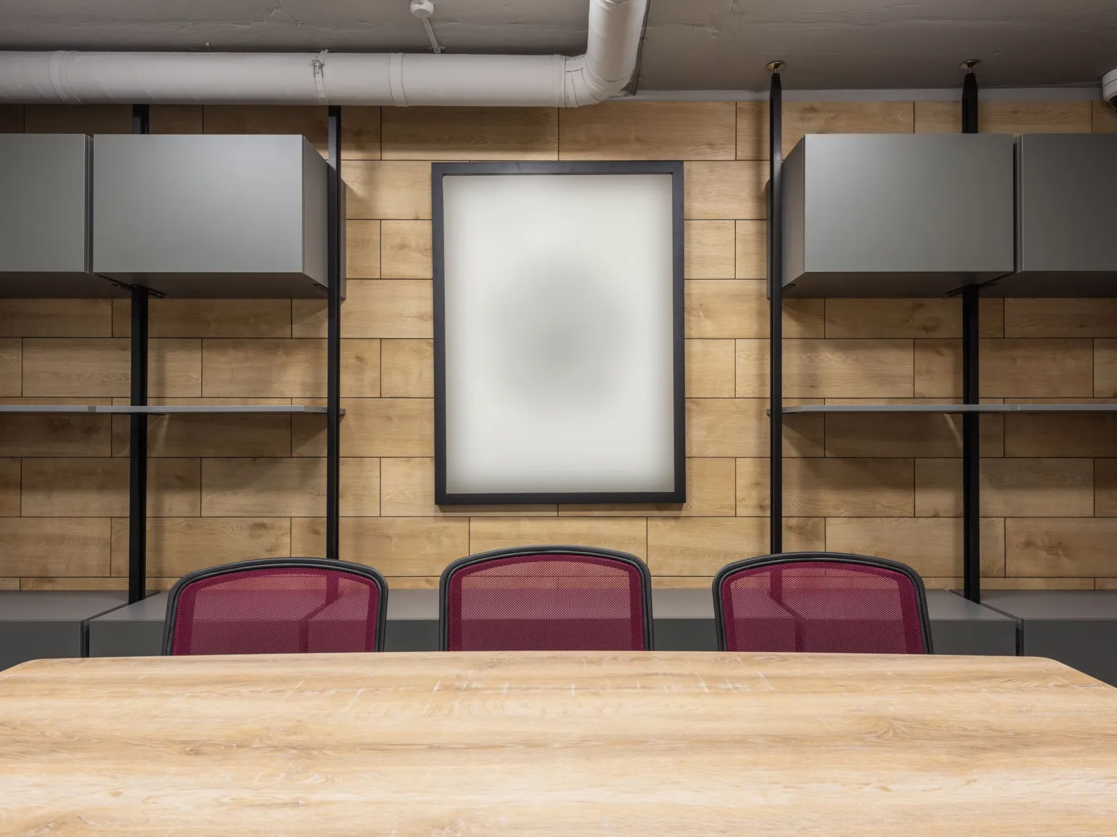 Symmetrical office room with wood-panel wall, magenta chairs and grey wall cabinets