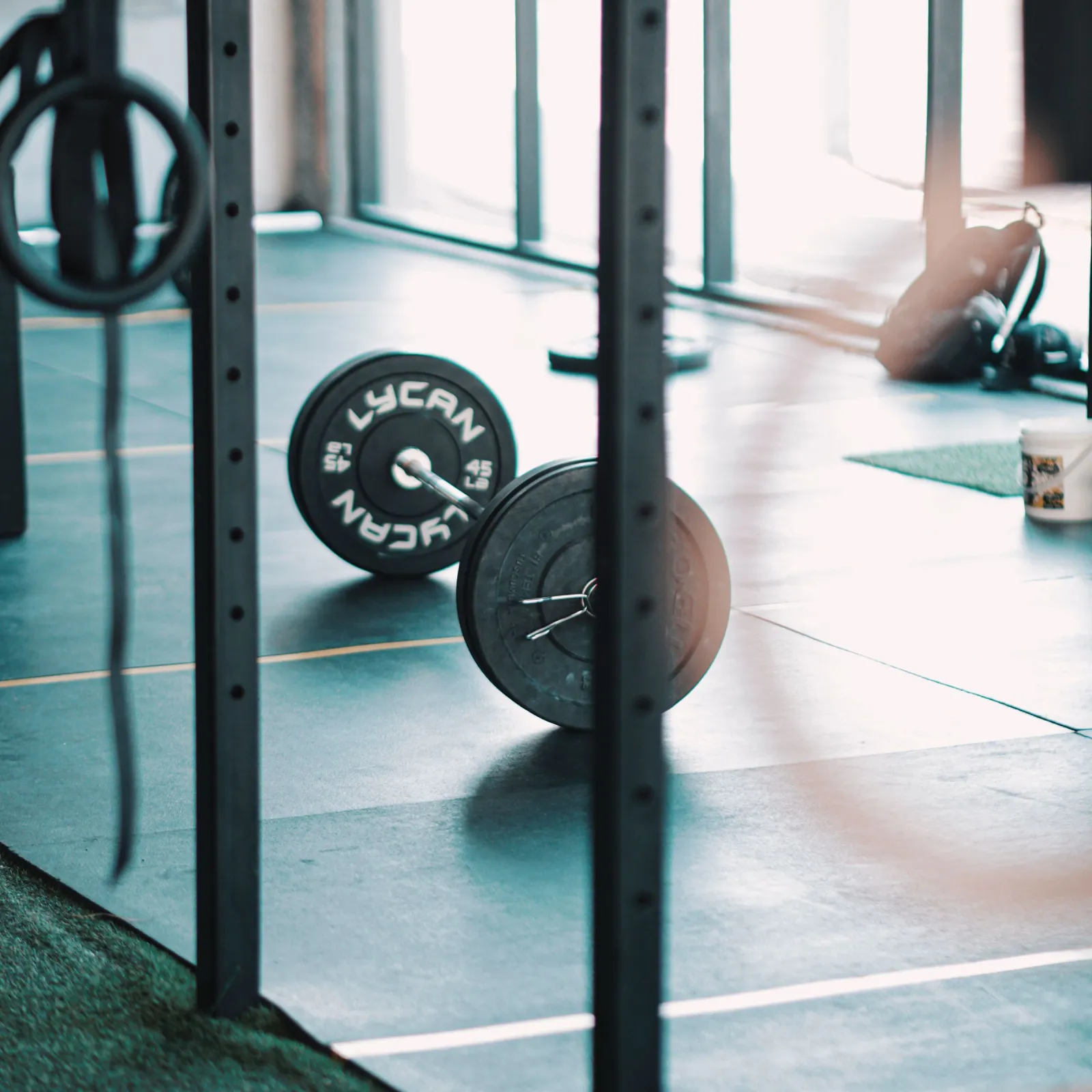 Loaded barbell resting on the floor of a sunlit functional training gym