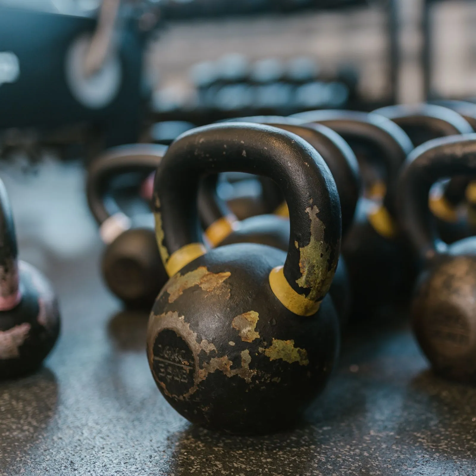 Close-up of worn cast-iron kettlebells standing on a rubber gym floor