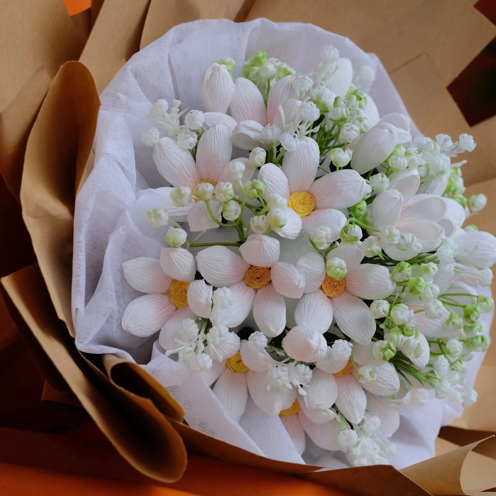 White daisy bouquet nestled in white tissue and kraft paper wrapping