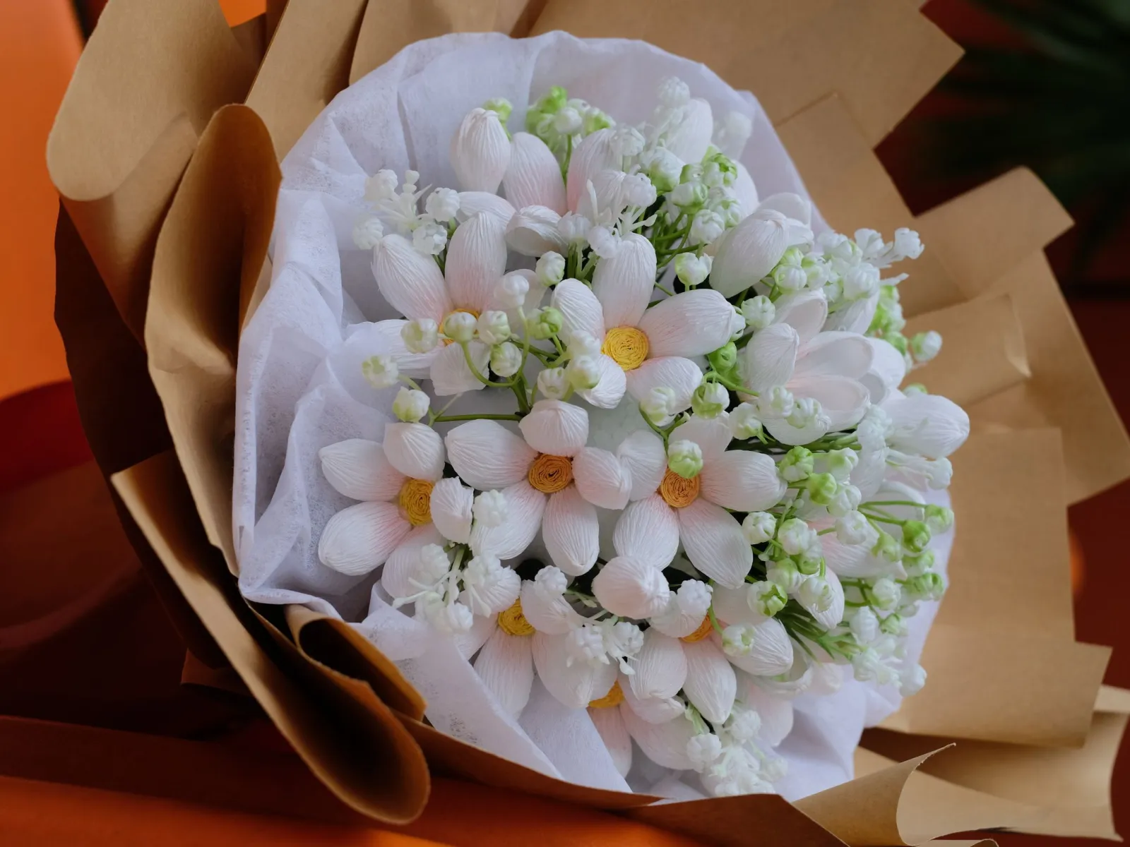 White daisy bouquet nestled in white tissue and kraft paper wrapping
