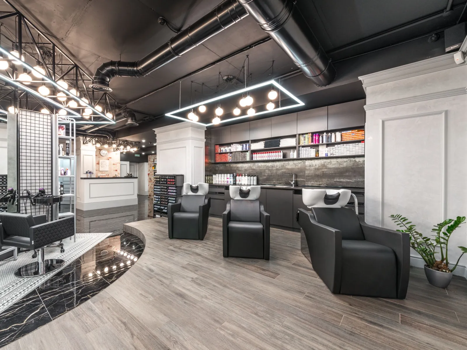 Modern salon interior with three backwash basin chairs and shelves of hair products