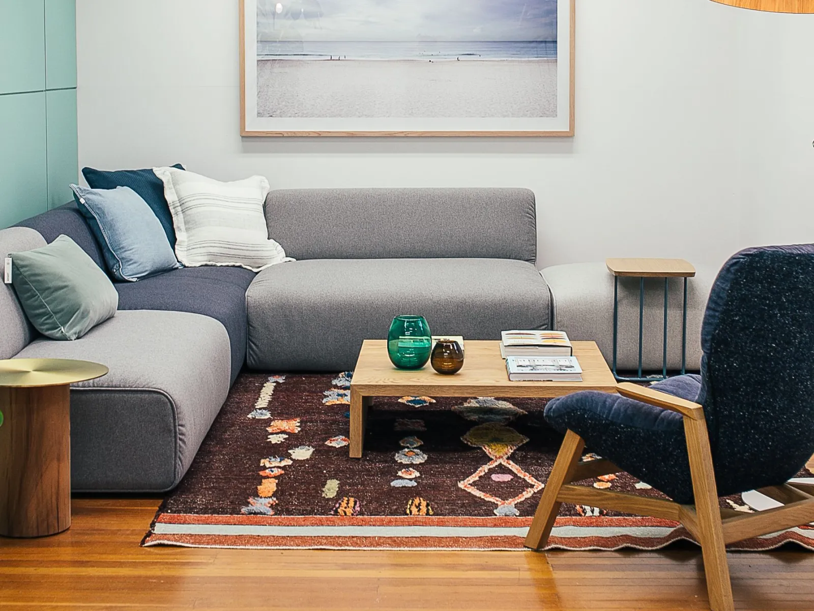 Gray modular sectional sofa with cushions on a patterned rug beside mint-green wall panels