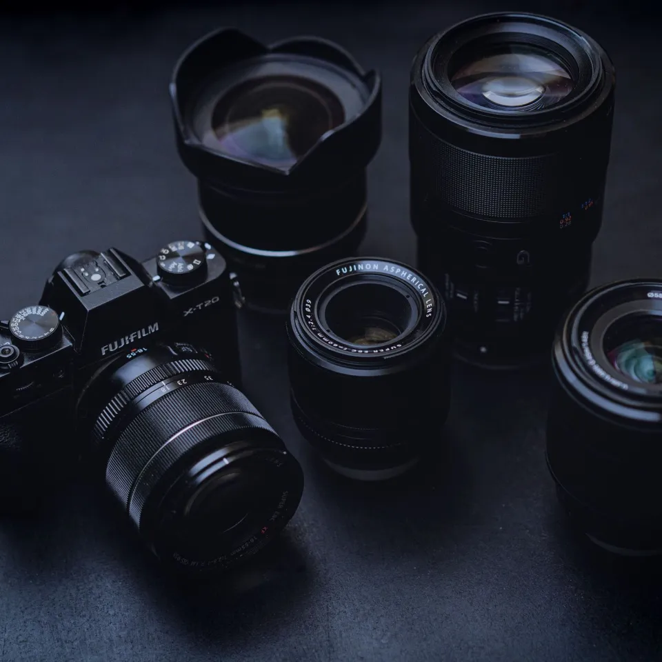 Mirrorless camera and four lenses arranged on a dark charcoal tabletop