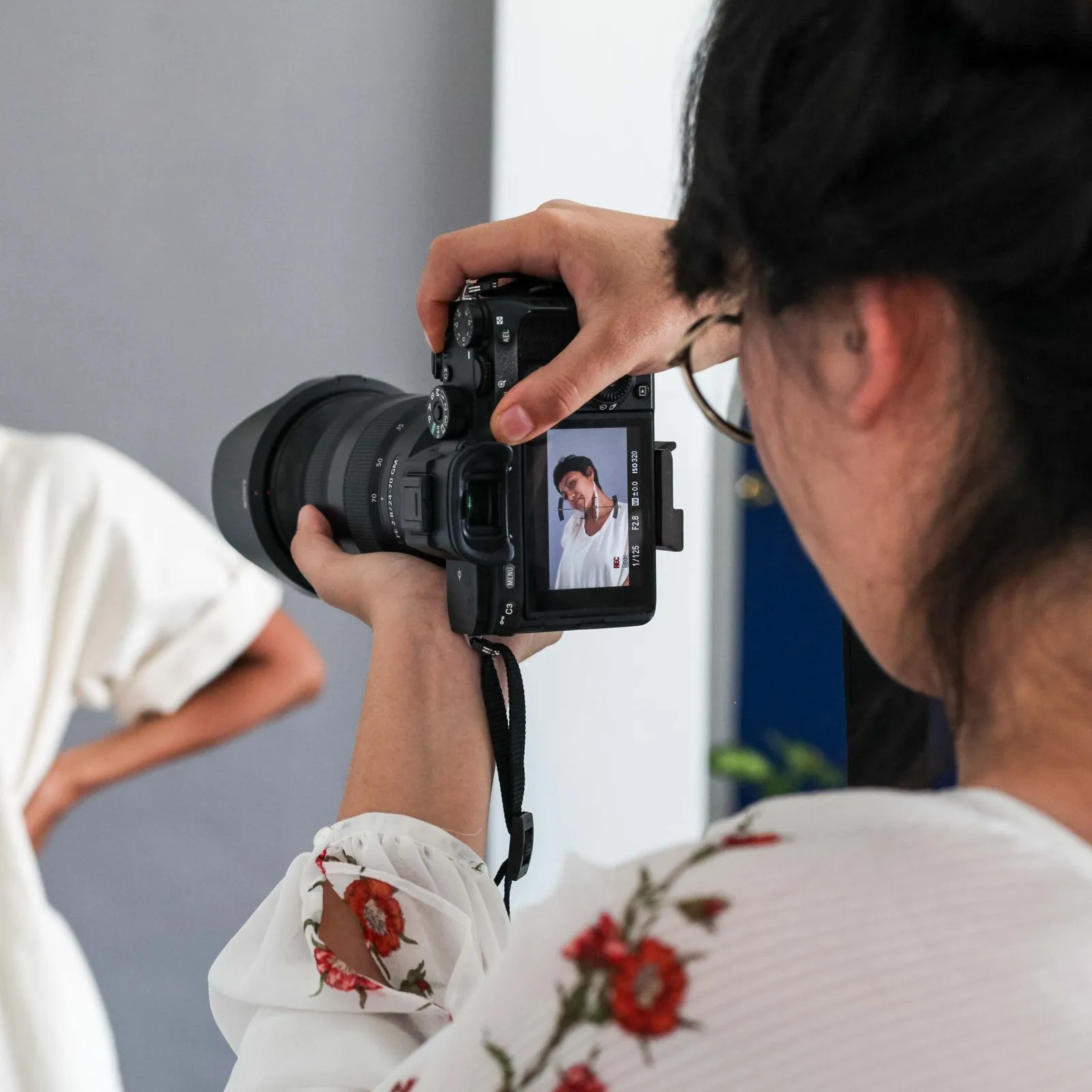 Over-the-shoulder view of a photographer framing a model on the camera's live screen