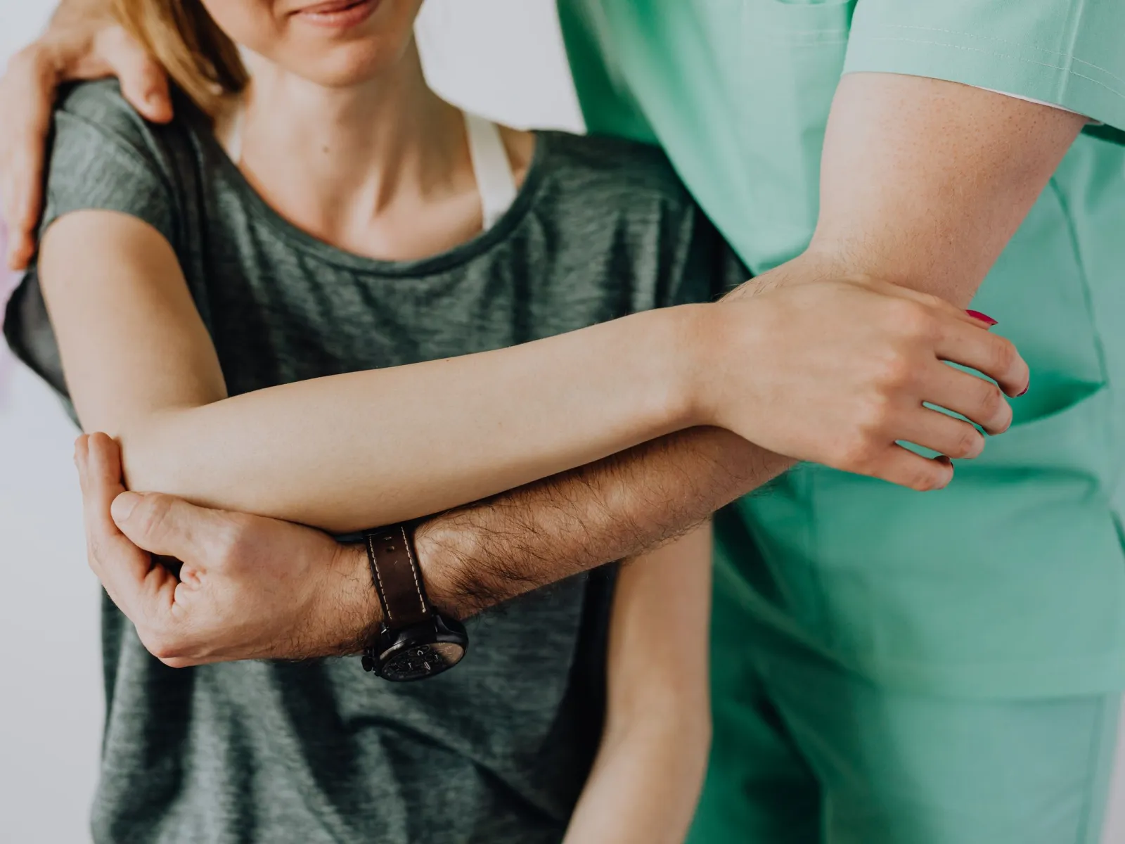 Close-up of a physiotherapist bending a patient's arm across her chest during assisted stretching