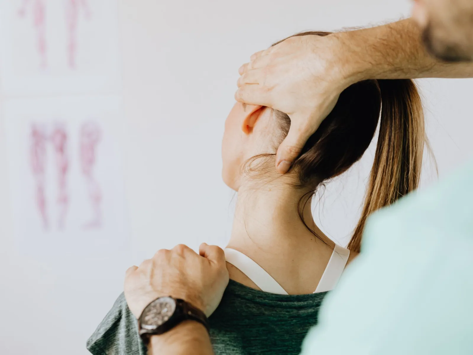 Therapist's hands supporting a woman's head and shoulder from behind during neck treatment