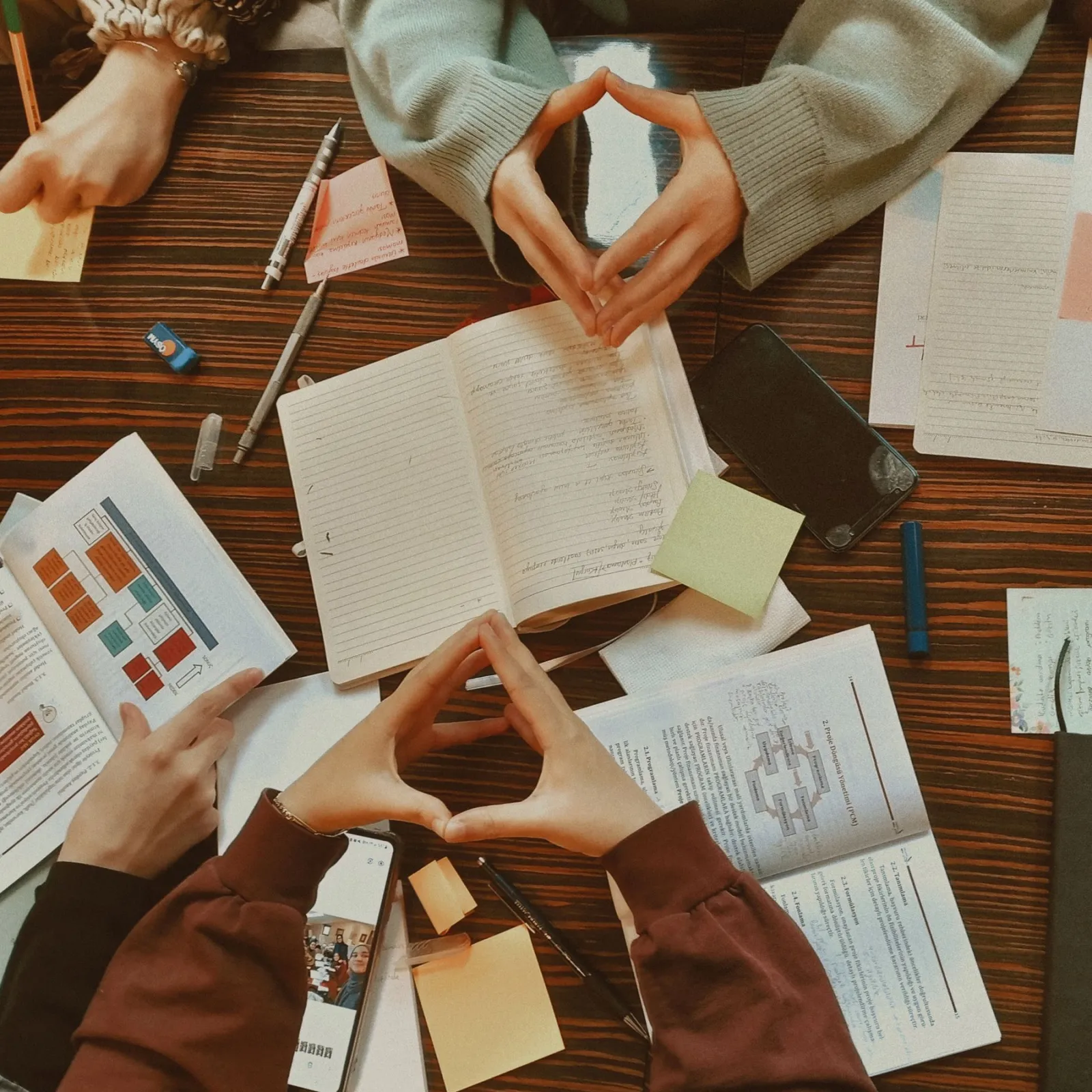 Overhead view of students' hands, notebooks and sticky notes during group study